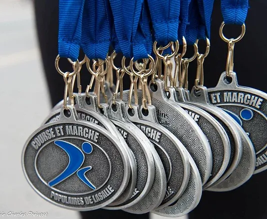 Close-up of several silver medals with blue ribbons for the "Course Populaire et Marche de LaSalle" event, featuring a logo of a stylized running figure.