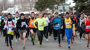 A large group of runners wearing numbered bibs participate in the Kilomaîtres LaSalle road race during a cold weather day, with spectators in the background.